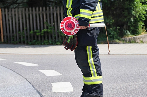 Ein Polizist oder Feuerwehrmann zeigt die rote Kelle